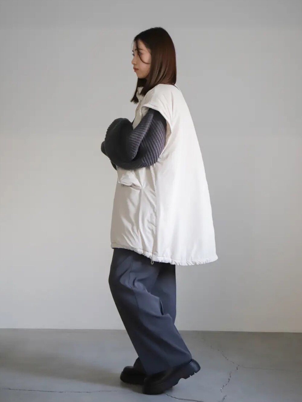 グレー系のニット/セーター、グレー系のスラックス、ホワイト系のダウンジャケット/コートを着用したレディースの冬コーディネートの2枚目の写真