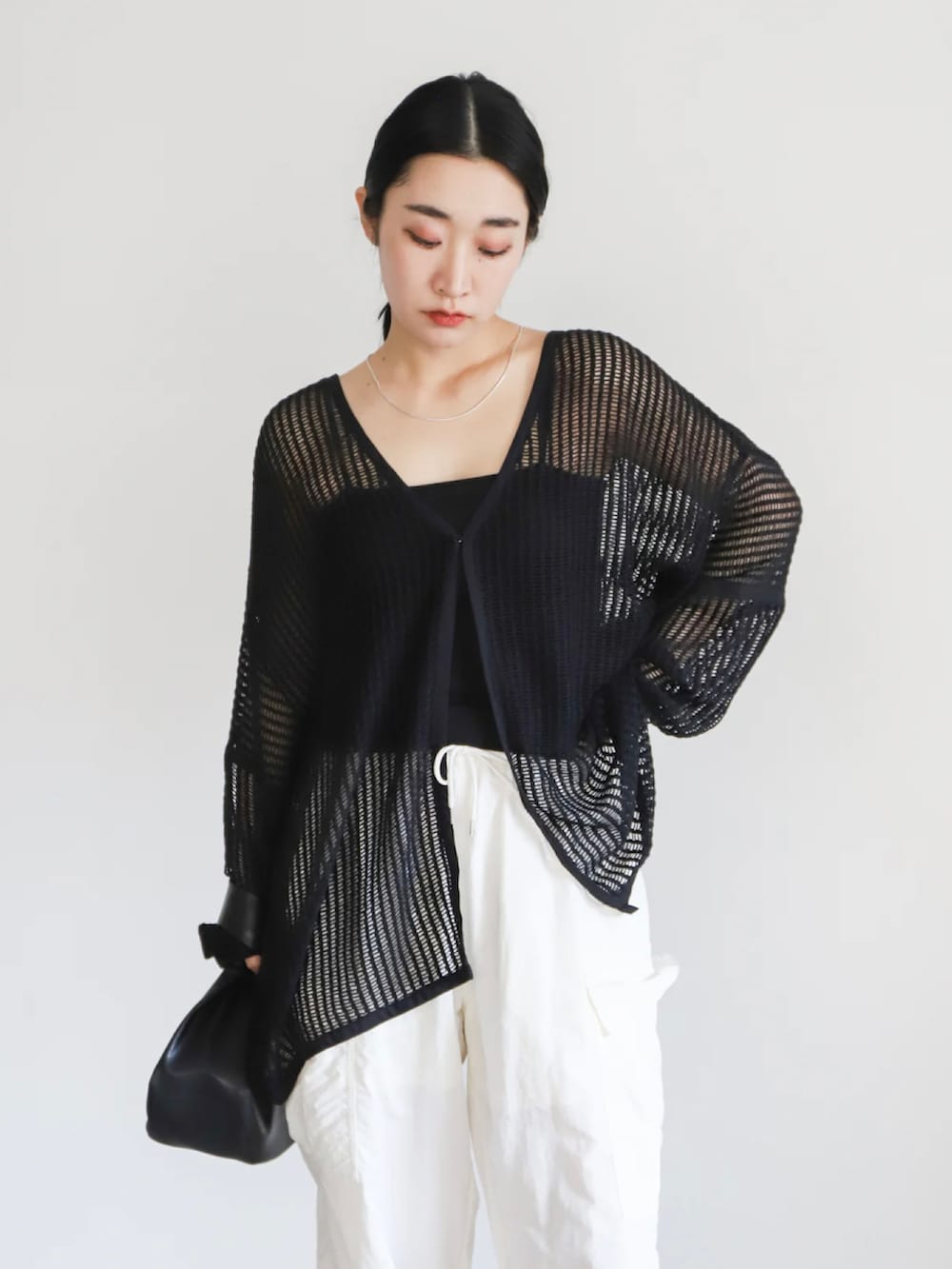 ブラック系のカーディガン/ボレロ、ブラック系のキャミソール、ホワイト系のカーゴパンツを着用したレディースの春コーディネートの5枚目の写真