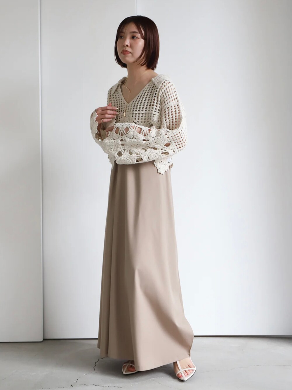 ホワイト系のニット/セーター、ベージュ系のジャンパースカート、ホワイト系のキャミソールを着用したレディースの春コーディネートの4枚目の写真