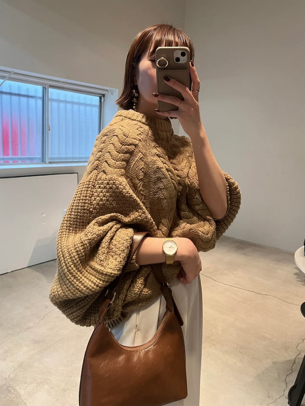 ベージュ系のニット/セーター、ホワイト系のスラックス、ブラウン系のハンドバッグを着用したレディースの冬コーディネートの3枚目の写真