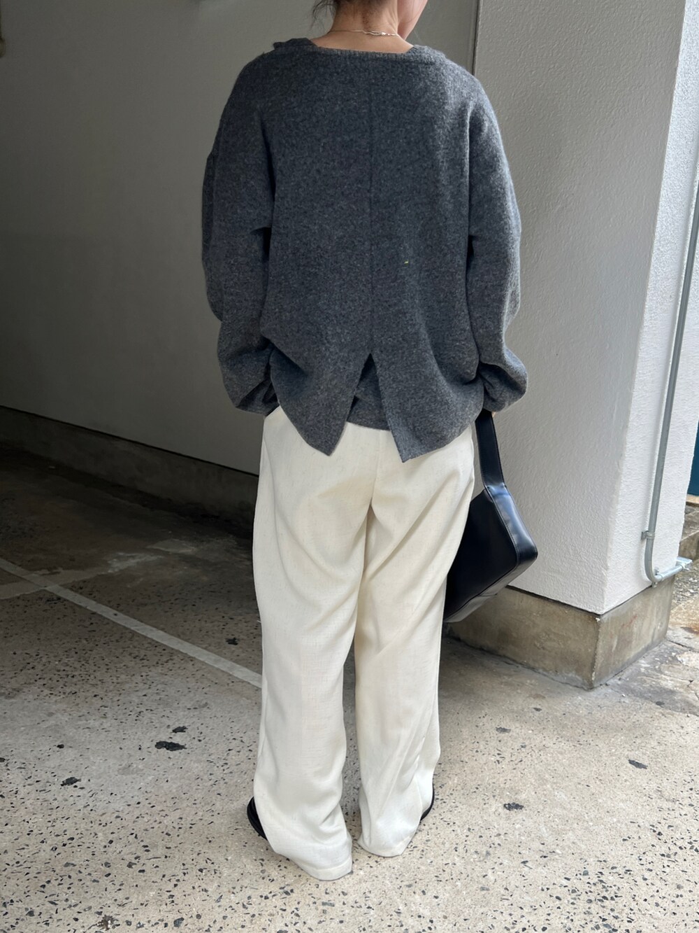 グレー系のニット/セーター、ベージュ系のスラックス、ブラック系のショルダーバッグを着用したレディースの秋コーディネートの3枚目の写真