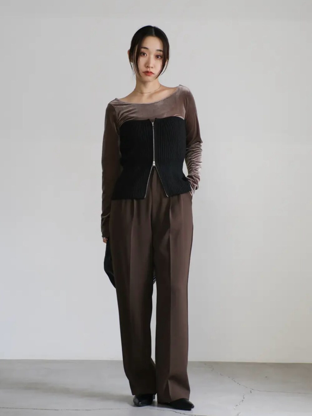 ブラウン系のTシャツ/カットソー、ブラック系のベスト、ブラウン系のスラックスを着用したレディースの秋コーディネートの3枚目の写真