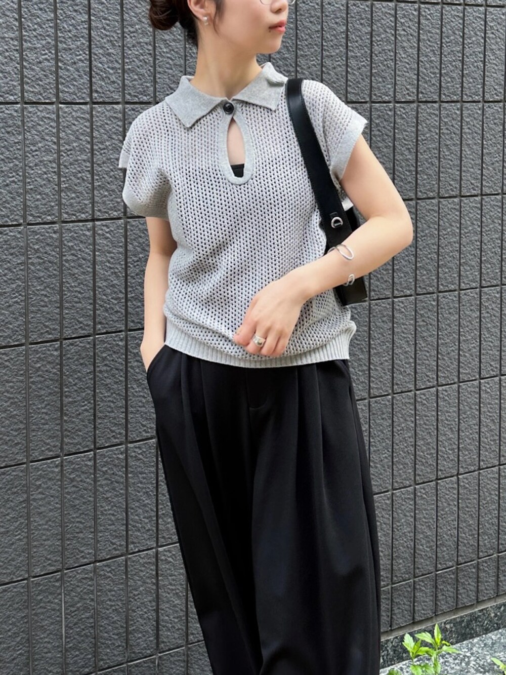 グレー系のニット/セーター、ブラック系のスラックス、ブラック系のショルダーバッグを着用したレディースの春コーディネートの4枚目の写真