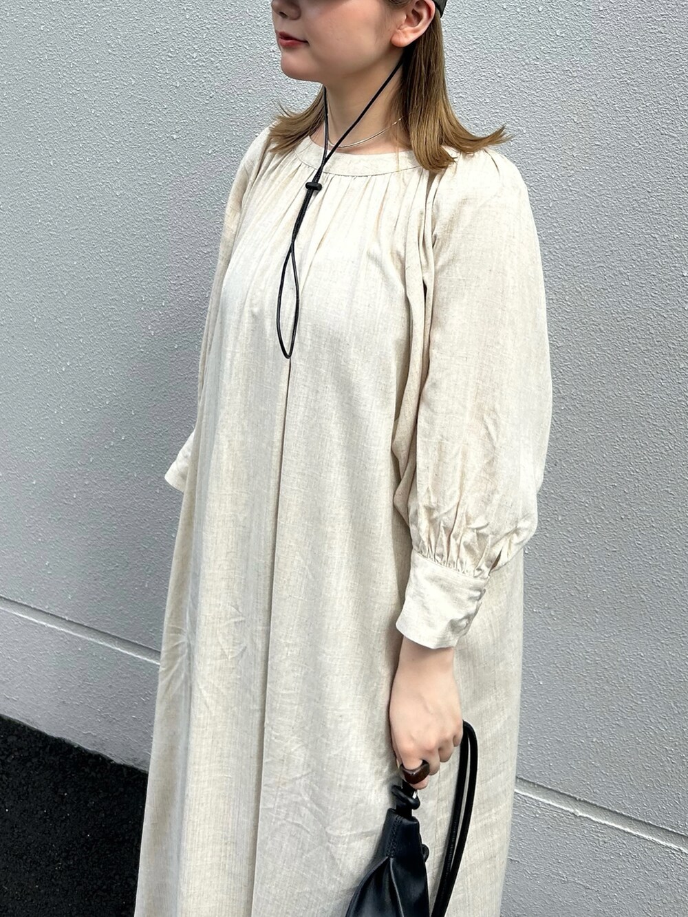 ベージュ系のワンピース、ブラック系のショルダーバッグ、グリーン系のキャップを着用したレディースの夏コーディネートの3枚目の写真