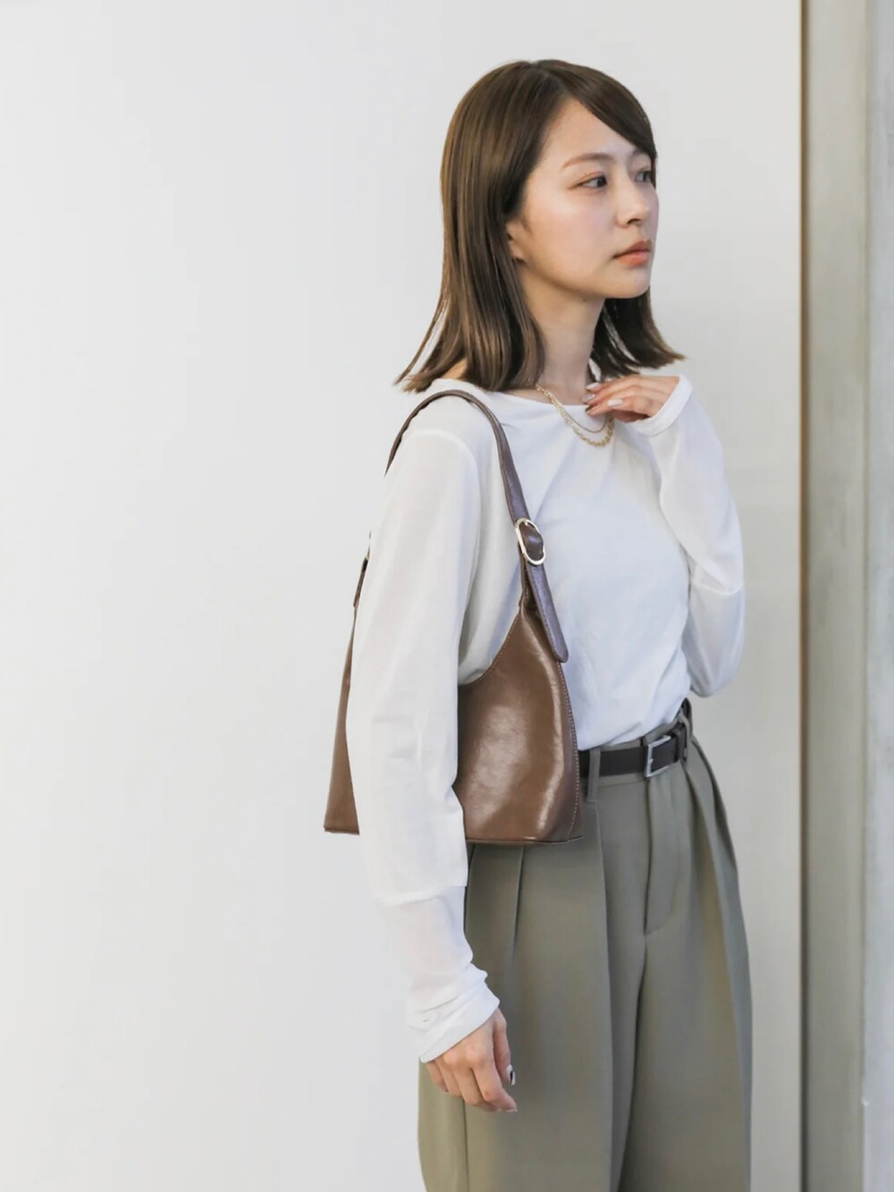 ホワイト系のTシャツ/カットソー、ベージュ系のスラックス、ブラウン系のハンドバッグを着用したレディースの冬コーディネートの5枚目の写真