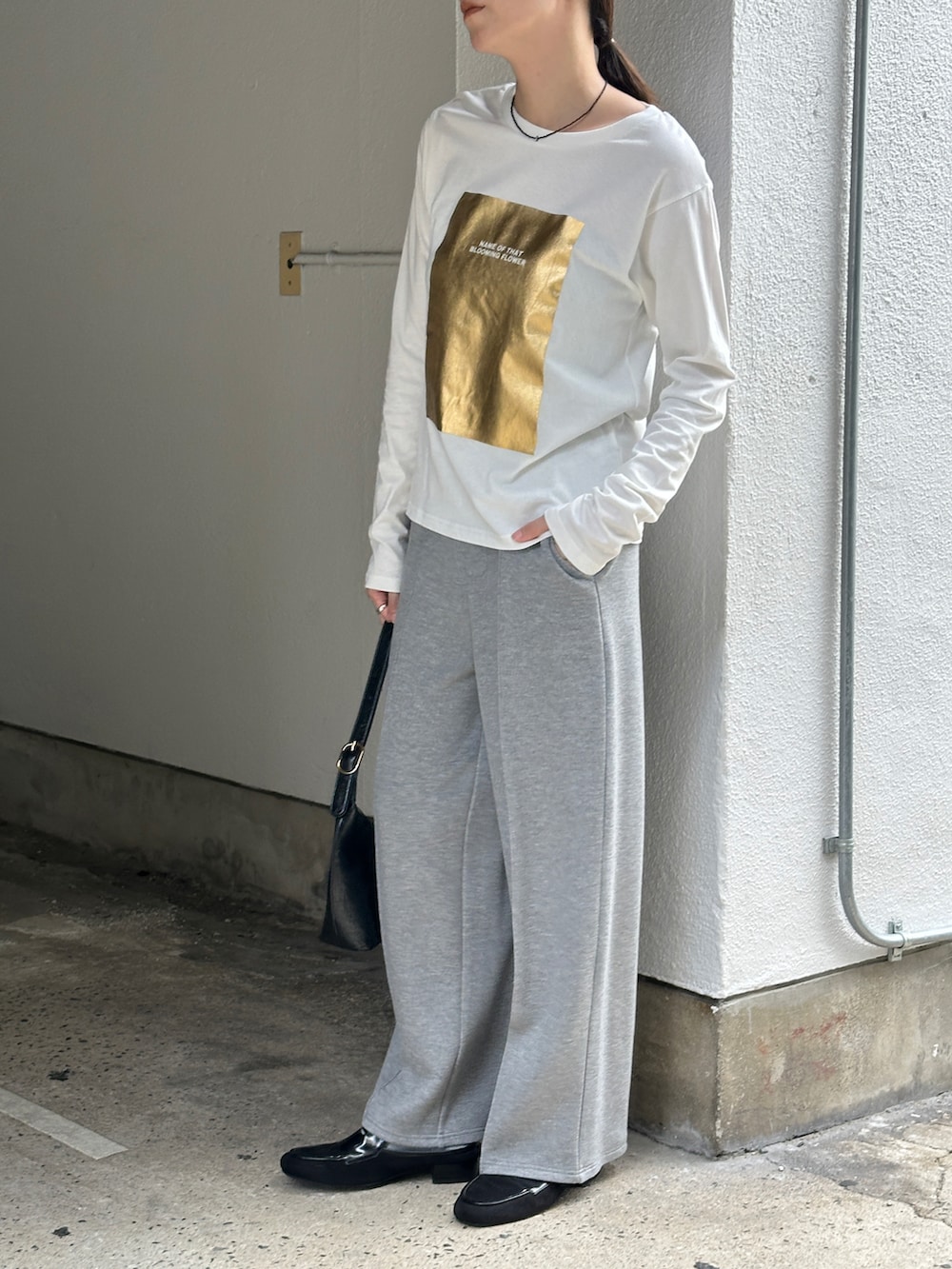 ホワイト系のTシャツ/カットソー、グレー系のその他パンツ、ブラック系のローファーを着用したレディースの秋コーディネートの2枚目の写真