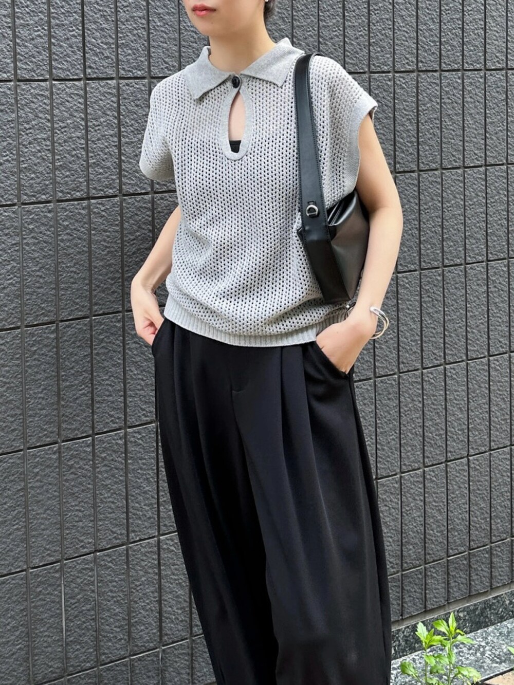 グレー系のニット/セーター、ブラック系のスラックス、ブラック系のショルダーバッグを着用したレディースの春コーディネートの5枚目の写真