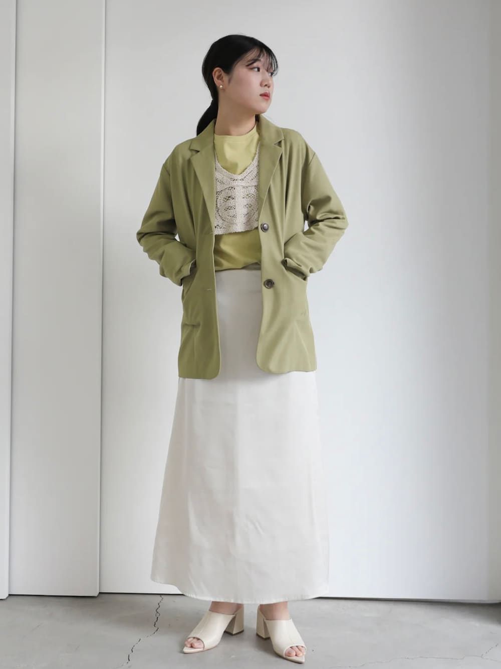 グリーン系のテーラードジャケット、ホワイト系のスカート、グリーン系のTシャツ/カットソーを着用したレディースの冬コーディネートの2枚目の写真