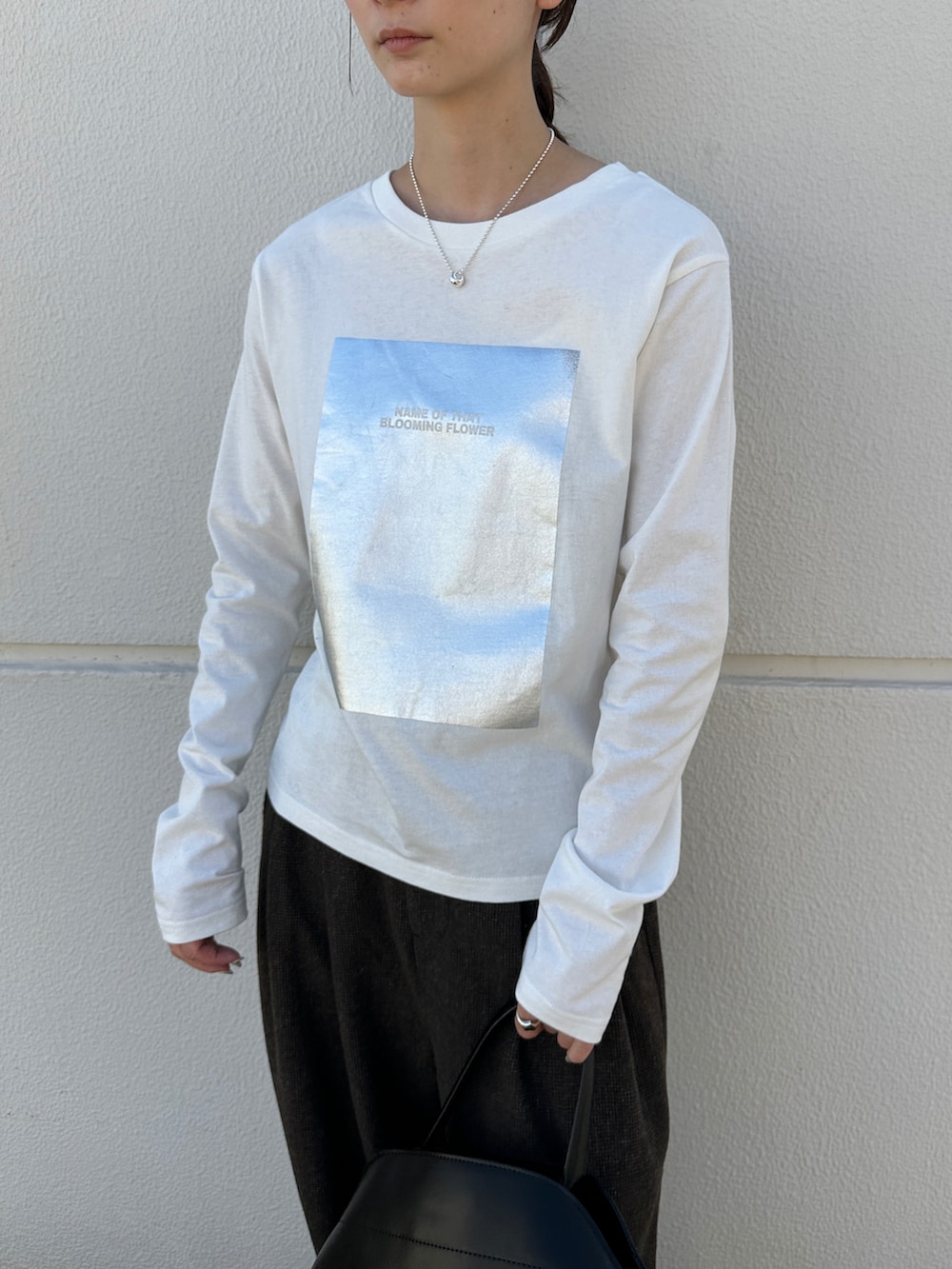 ホワイト系のTシャツ/カットソー、ブラック系のハンドバッグ、ブラック系のローファーを着用したレディースの秋コーディネートの5枚目の写真