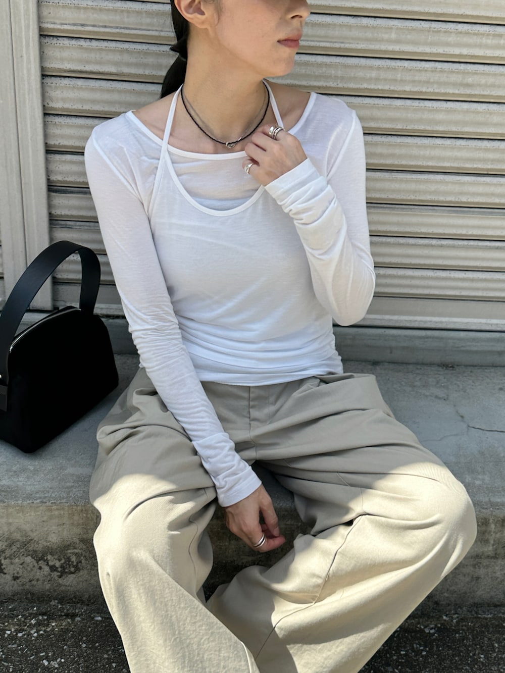 ホワイト系のTシャツ/カットソー、ブラック系のハンドバッグ、ベージュ系のスラックスを着用したレディースの秋コーディネートの2枚目の写真