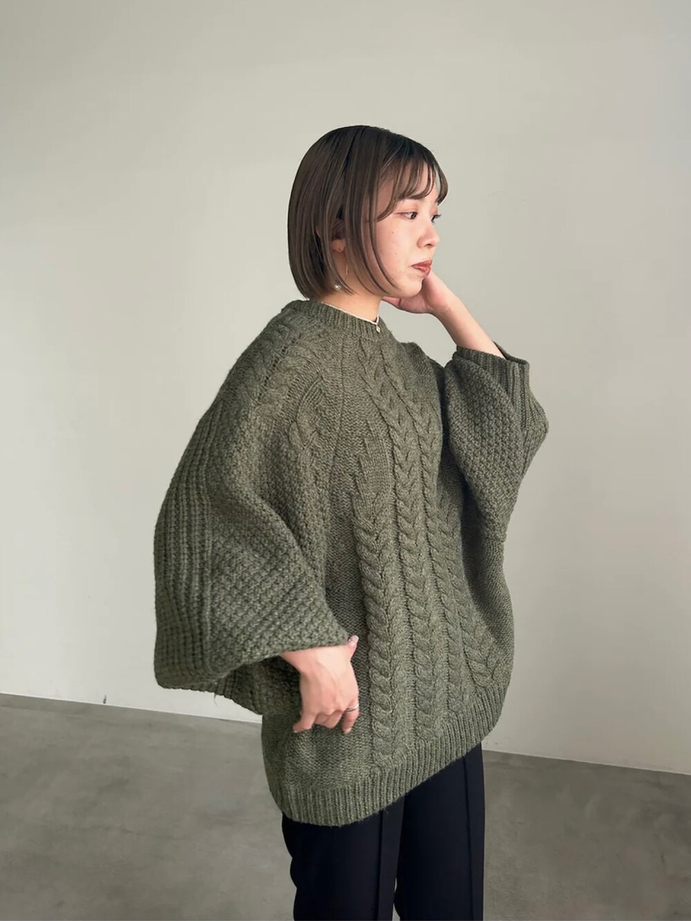 グリーン系のニット/セーター、ブラック系のその他パンツを着用したレディースの冬コーディネートの3枚目の写真