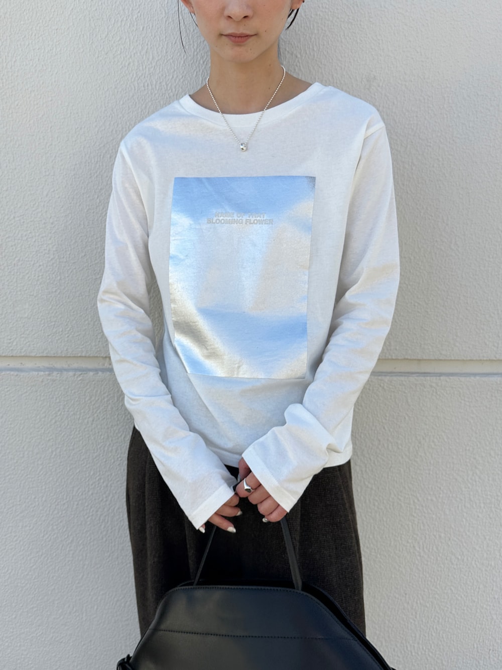 ホワイト系のTシャツ/カットソー、ブラック系のハンドバッグ、ブラック系のローファーを着用したレディースの秋コーディネートの4枚目の写真