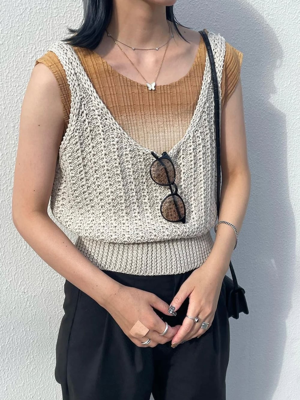 ホワイト系のベスト、ブラウン系のサングラスを着用したレディースの夏コーディネートの2枚目の写真