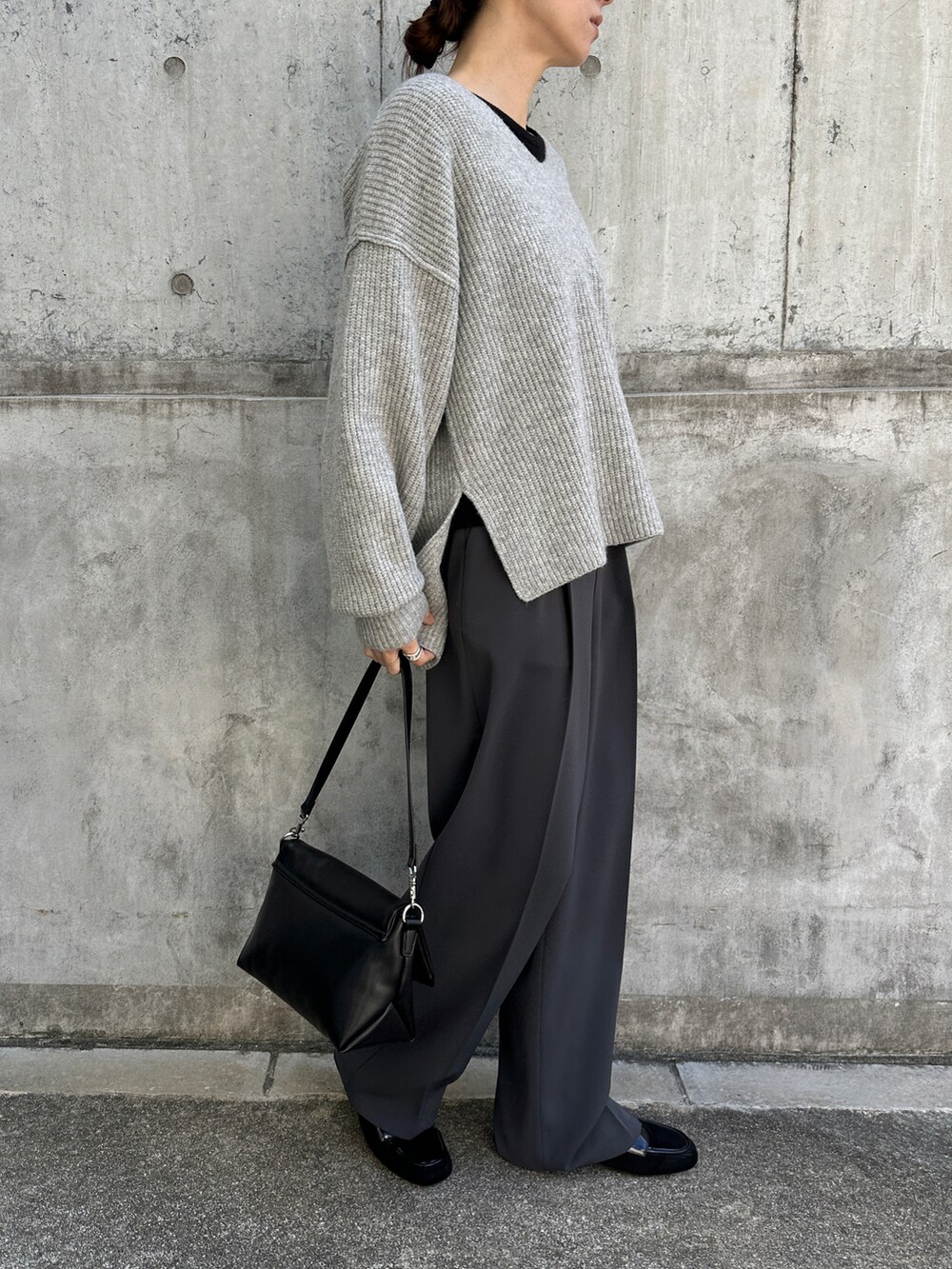 グレー系のニット/セーター、ブラック系のTシャツ/カットソー、グレー系のスラックスを着用したレディースの冬コーディネートの3枚目の写真