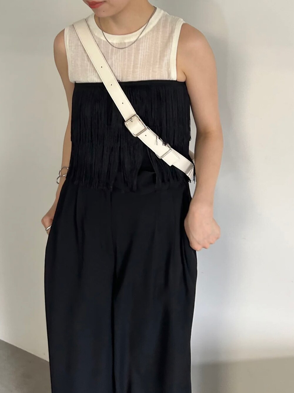 ブラック系のベスト、ホワイト系のニット/セーター、ブラック系のスラックスを着用したレディースの春コーディネートの3枚目の写真