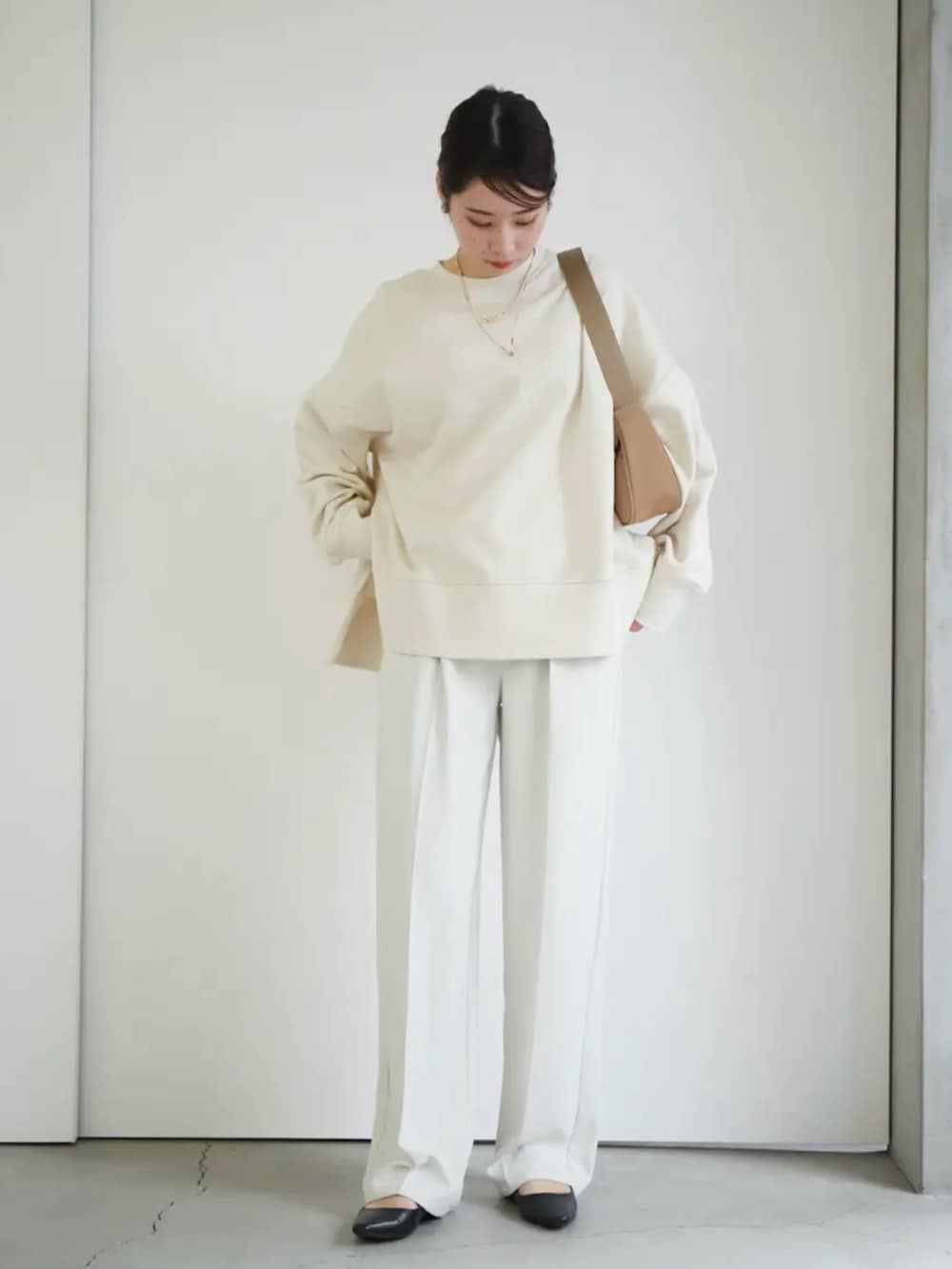 ホワイト系のスウェット、ホワイト系のスラックス、ベージュ系のショルダーバッグを着用したレディースの冬コーディネートの2枚目の写真