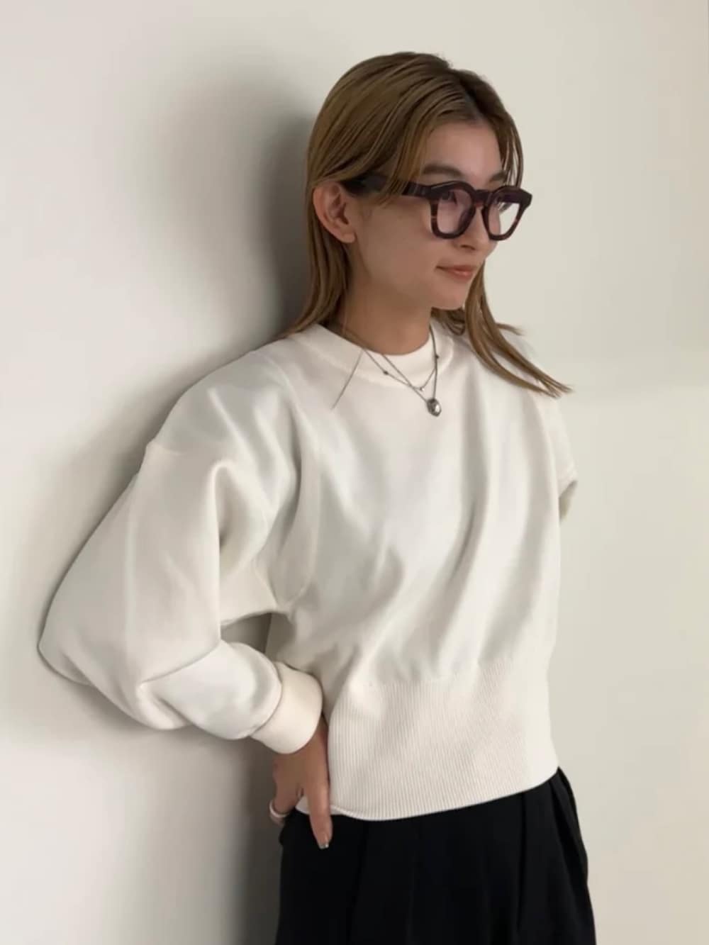 ホワイト系のニット/セーター、ブラック系のスラックスを着用したレディースの冬コーディネートの2枚目の写真