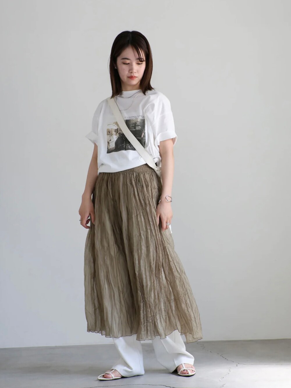 ホワイト系のTシャツ/カットソー、ホワイト系のスラックス、ブラウン系のワンピースを着用したレディースの夏コーディネートの2枚目の写真
