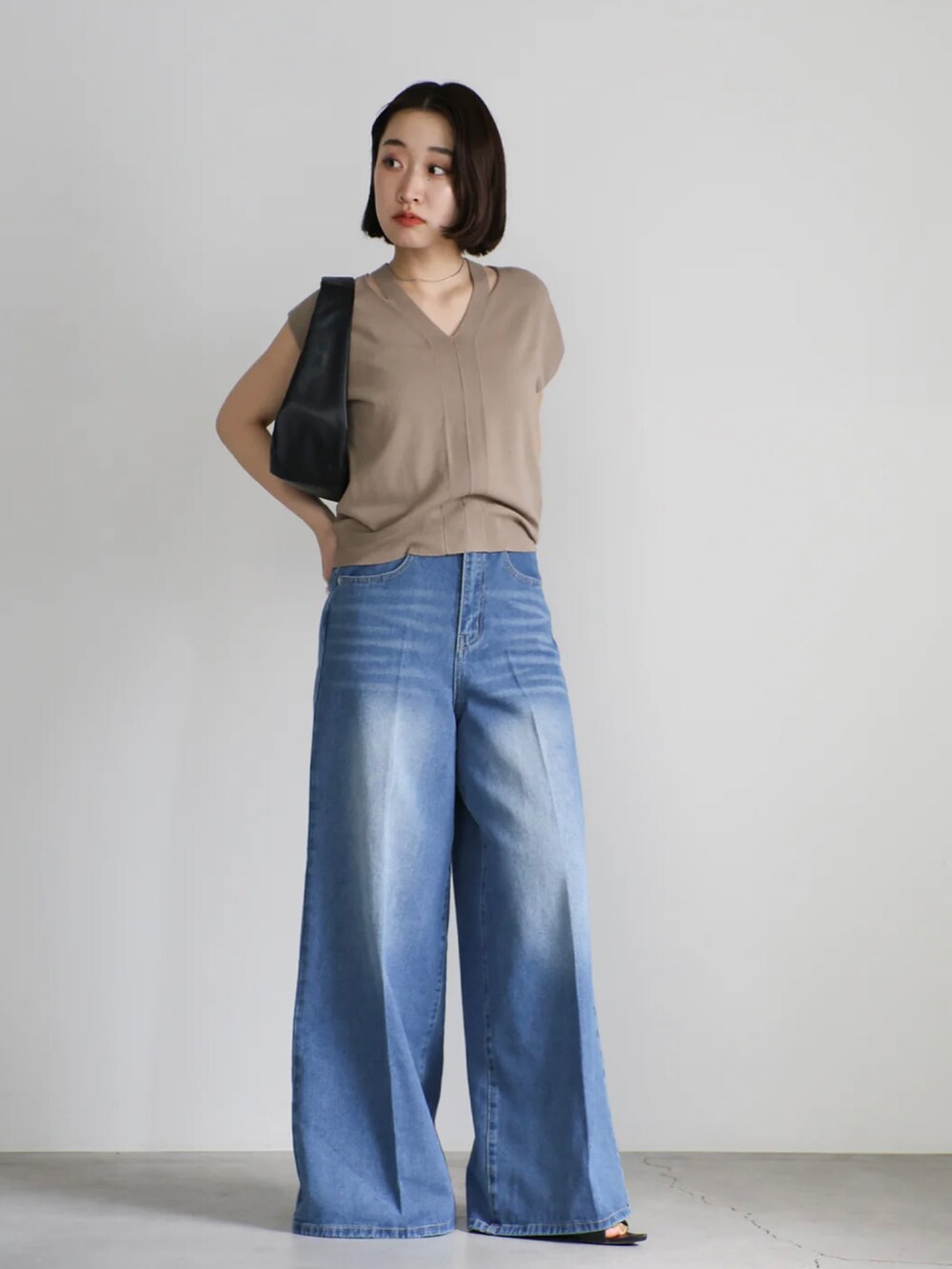 ベージュ系のニット/セーター、ブルー系のデニムパンツ、ブラック系のショルダーバッグを着用したレディースの夏コーディネートの2枚目の写真