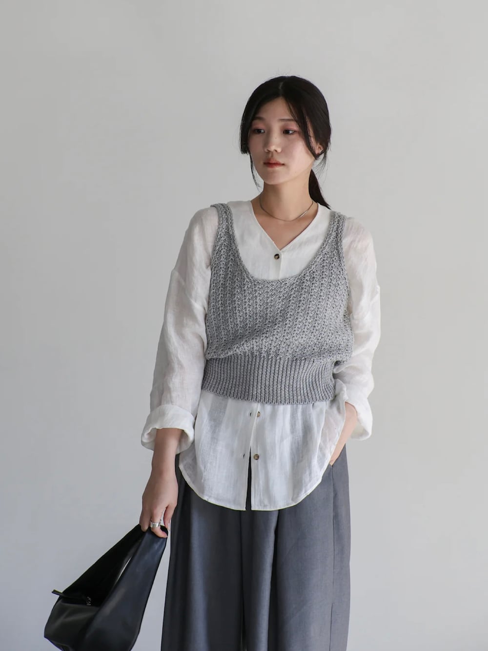 グレー系のベスト、ホワイト系のシャツ/ブラウス、グレー系のスラックスを着用したレディースの夏コーディネートの4枚目の写真