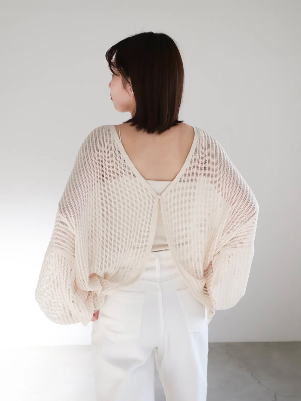 ホワイト系のカーディガン/ボレロ、ホワイト系のキャミソール、ゴールド系のネックレスを着用したレディースの春コーディネートの5枚目の写真