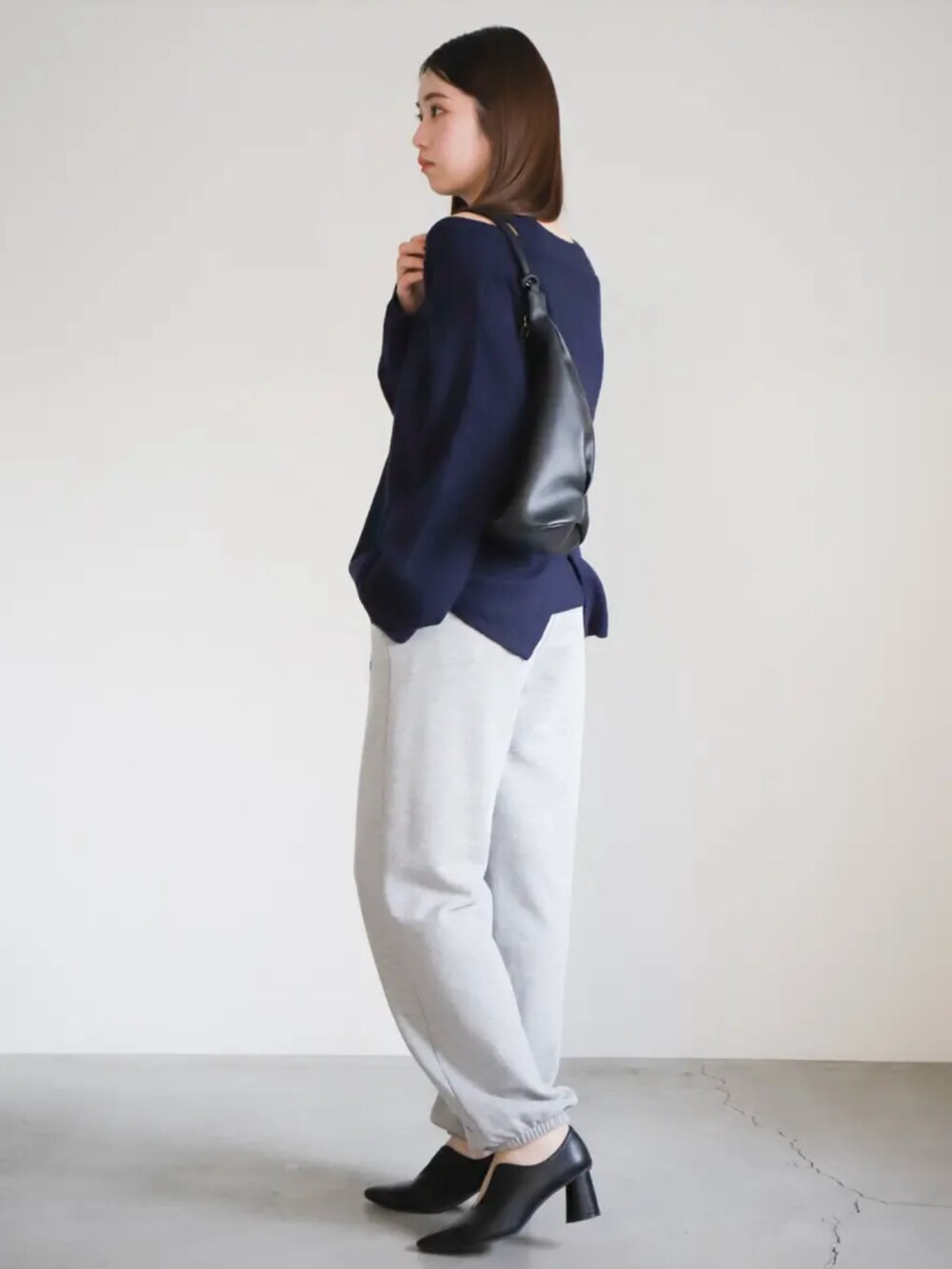 ブルー系のニット/セーター、グレー系のスウェットパンツ、ブラック系のショルダーバッグを着用したレディースの春コーディネートの2枚目の写真