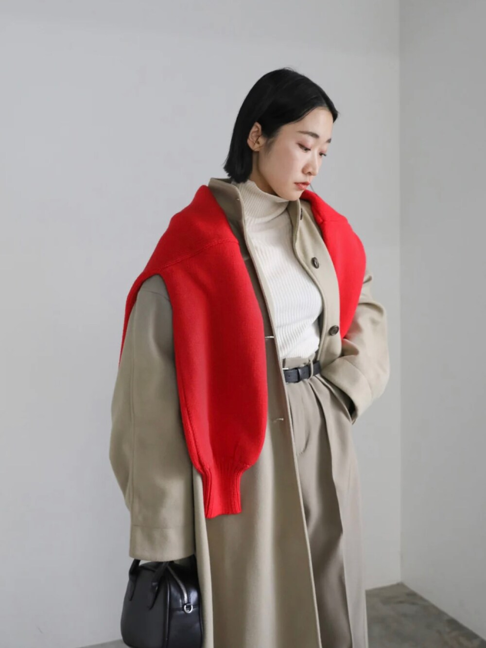 ベージュ系のステンカラーコート、レッド系のニット/セーター、ベージュ系のスラックスを着用したレディースの冬コーディネートの5枚目の写真