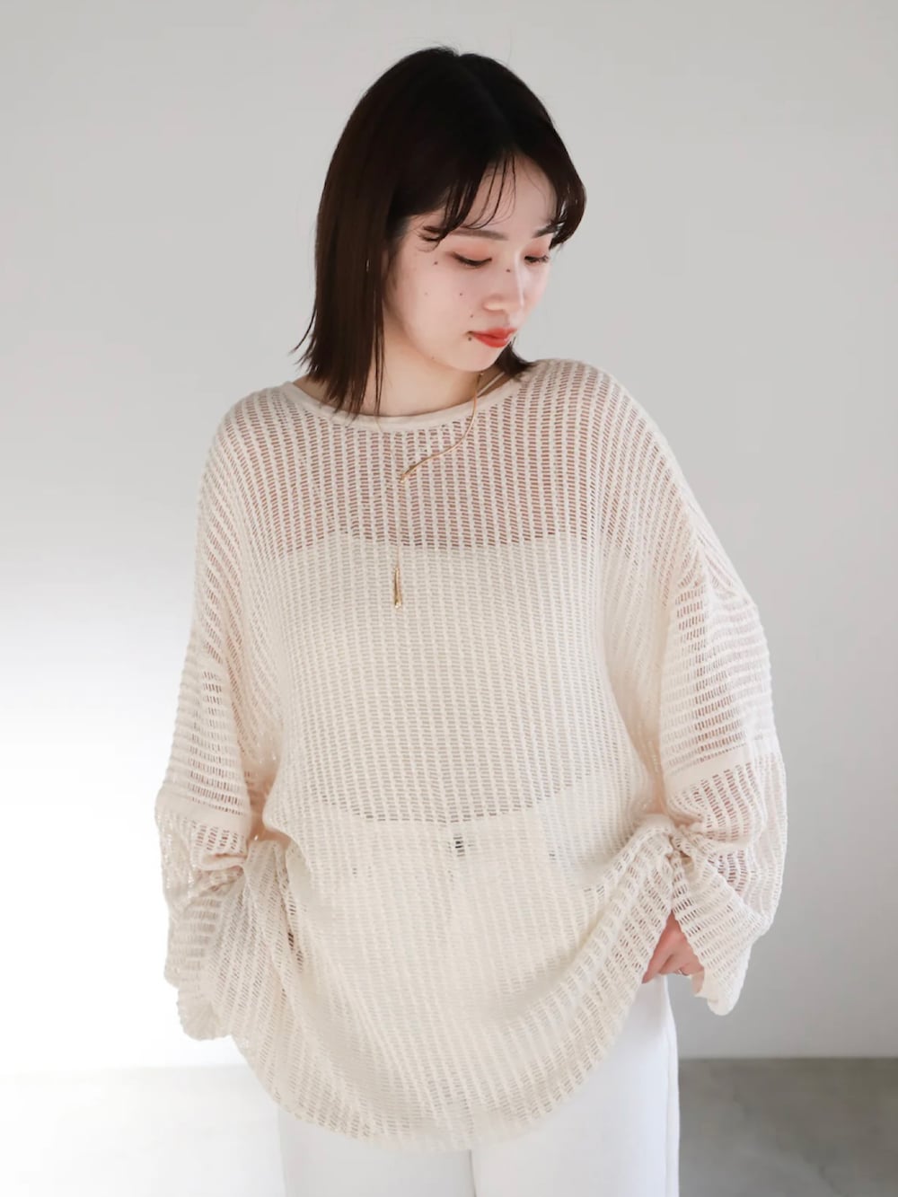 ホワイト系のカーディガン/ボレロ、ホワイト系のキャミソール、ゴールド系のネックレスを着用したレディースの春コーディネートの4枚目の写真