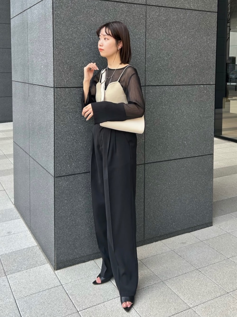 ブラック系のシャツ/ブラウス、ベージュ系のベスト、ホワイト系のショルダーバッグを着用したレディースの春コーディネートの2枚目の写真