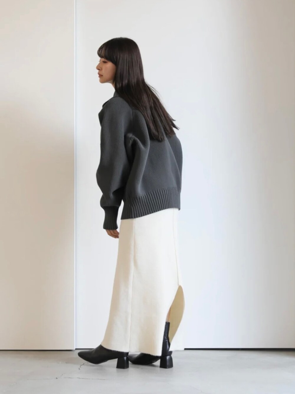グレー系のニット/セーター、ホワイト系のスカートを着用したレディースの秋コーディネートの4枚目の写真