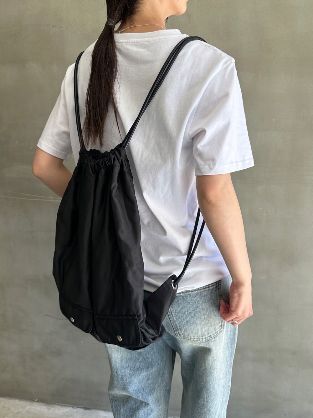 ホワイト系のTシャツ/カットソー、ブルー系のデニムパンツ、ブラック系のバックパック/リュックを着用したレディースの春コーディネートの5枚目の写真