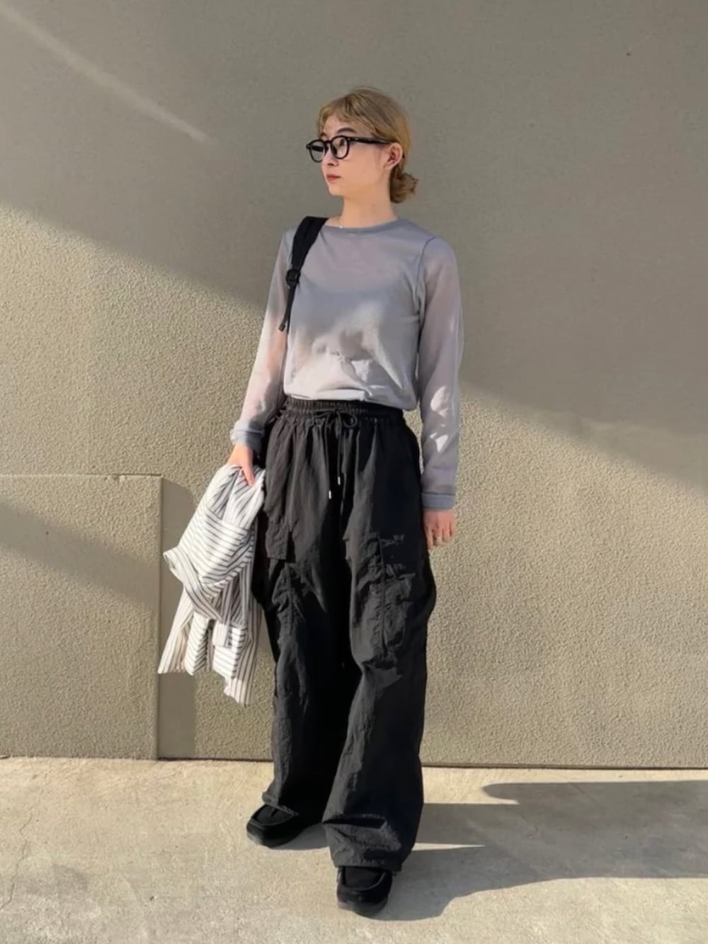 グレー系のニット/セーター、ホワイト系のシャツ/ブラウス、ブラック系のカーゴパンツを着用したレディースの春コーディネートの2枚目の写真