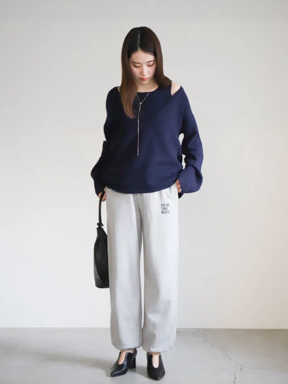 ブルー系のニット/セーター、グレー系のスウェットパンツ、ブラック系のショルダーバッグを着用したレディースの春コーディネートの3枚目の写真