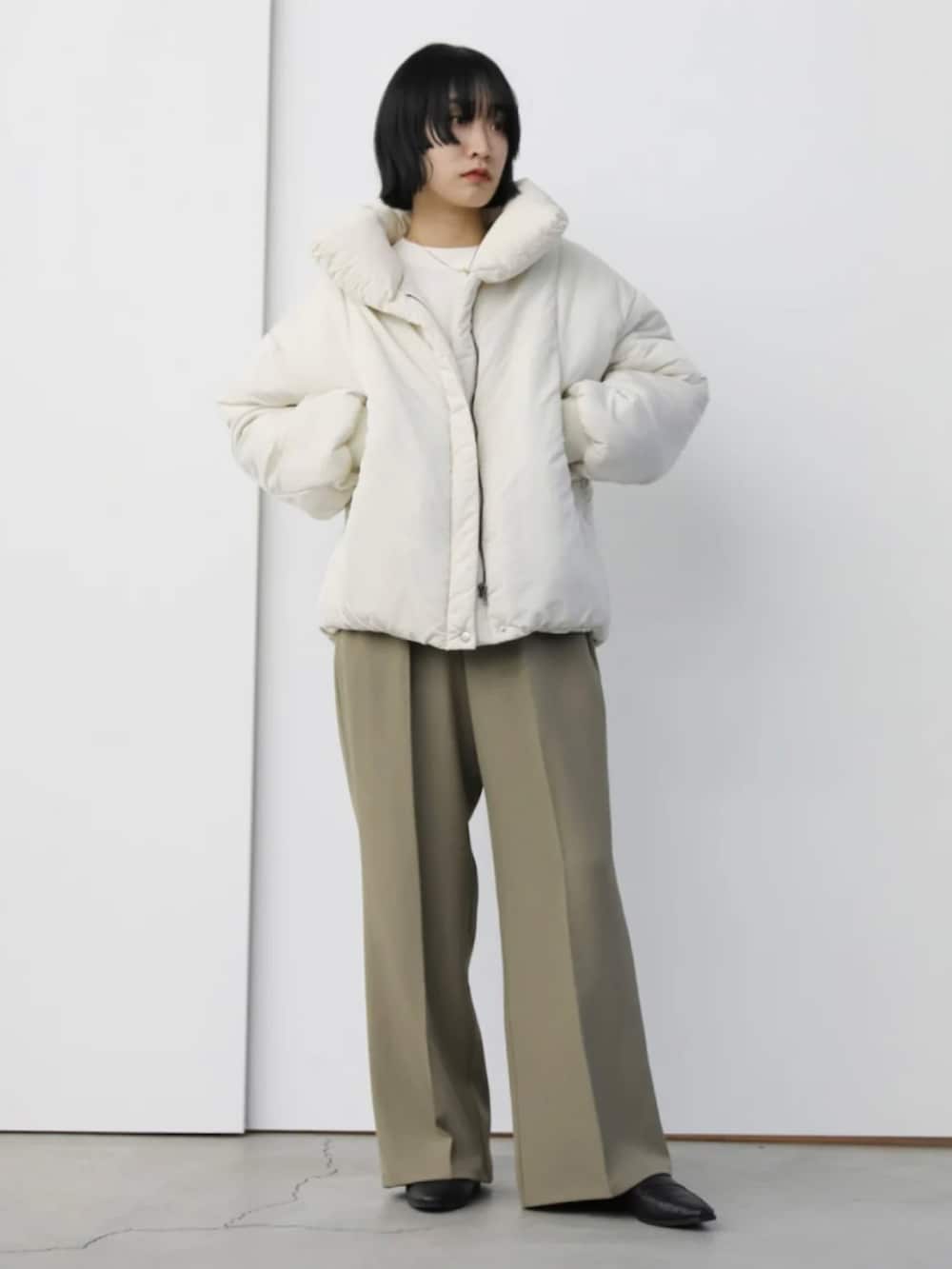 ホワイト系のダウンジャケット/コート、ベージュ系のスラックス、ホワイト系のニット/セーターを着用したレディースの秋コーディネートの3枚目の写真