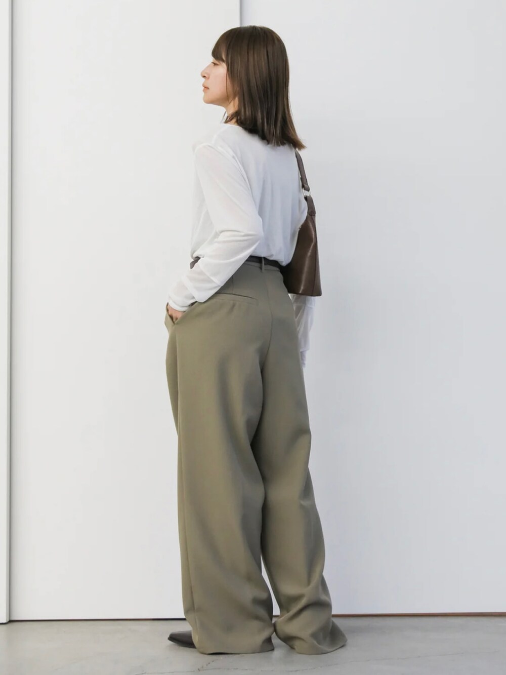 ホワイト系のTシャツ/カットソー、ベージュ系のスラックス、ブラウン系のハンドバッグを着用したレディースの冬コーディネートの2枚目の写真