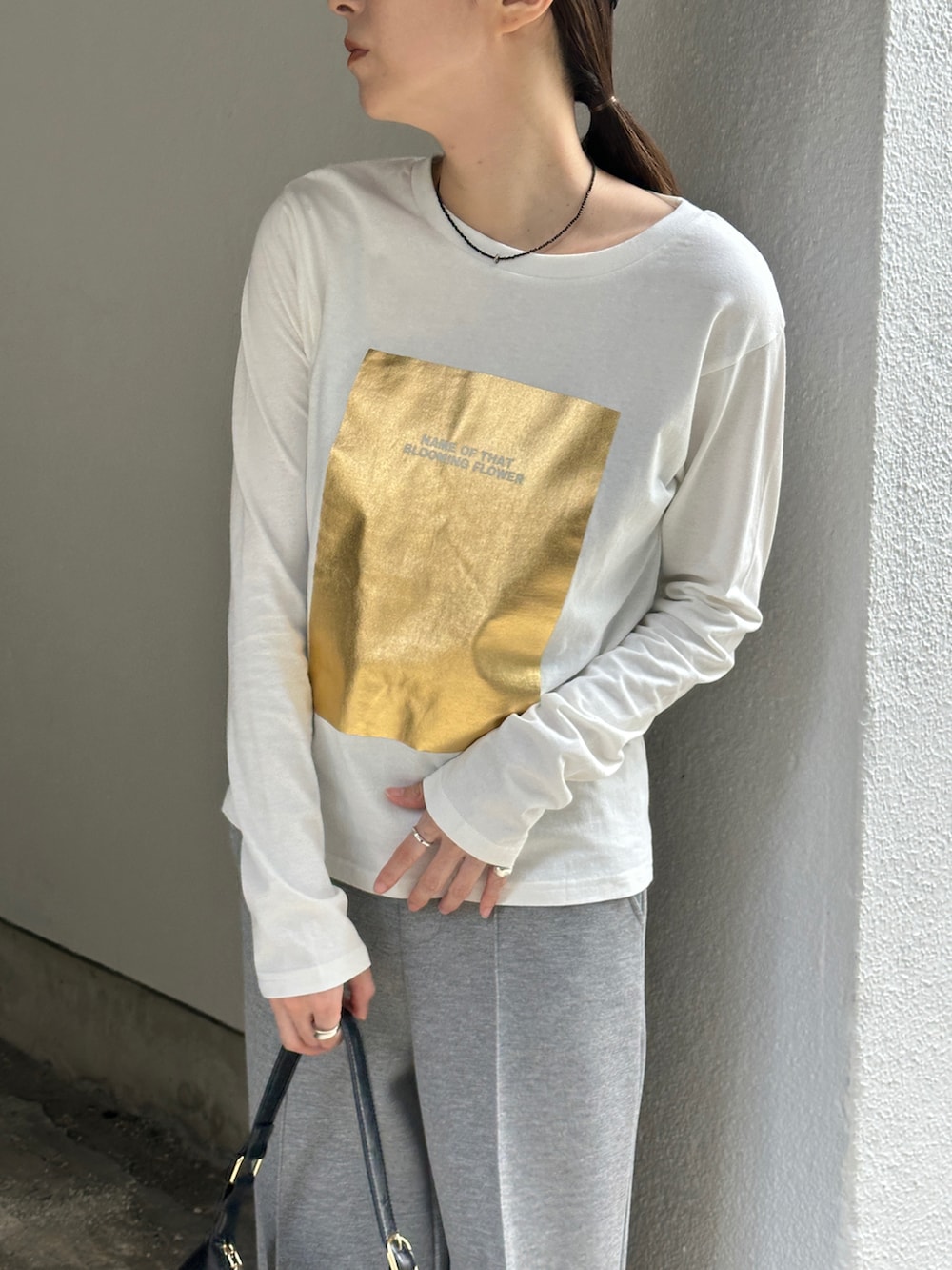 ホワイト系のTシャツ/カットソー、グレー系のその他パンツ、ブラック系のローファーを着用したレディースの秋コーディネートの3枚目の写真