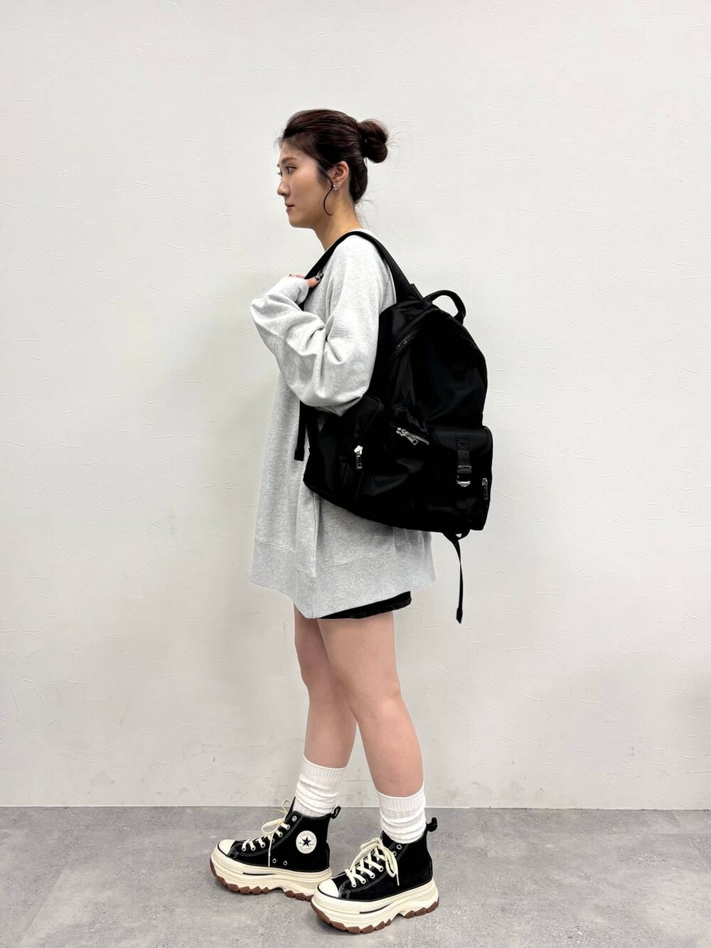 グレー系のスウェット、ブラック系のスニーカー、ブラウン系のデニムスカートを着用したレディースの冬コーディネートの3枚目の写真