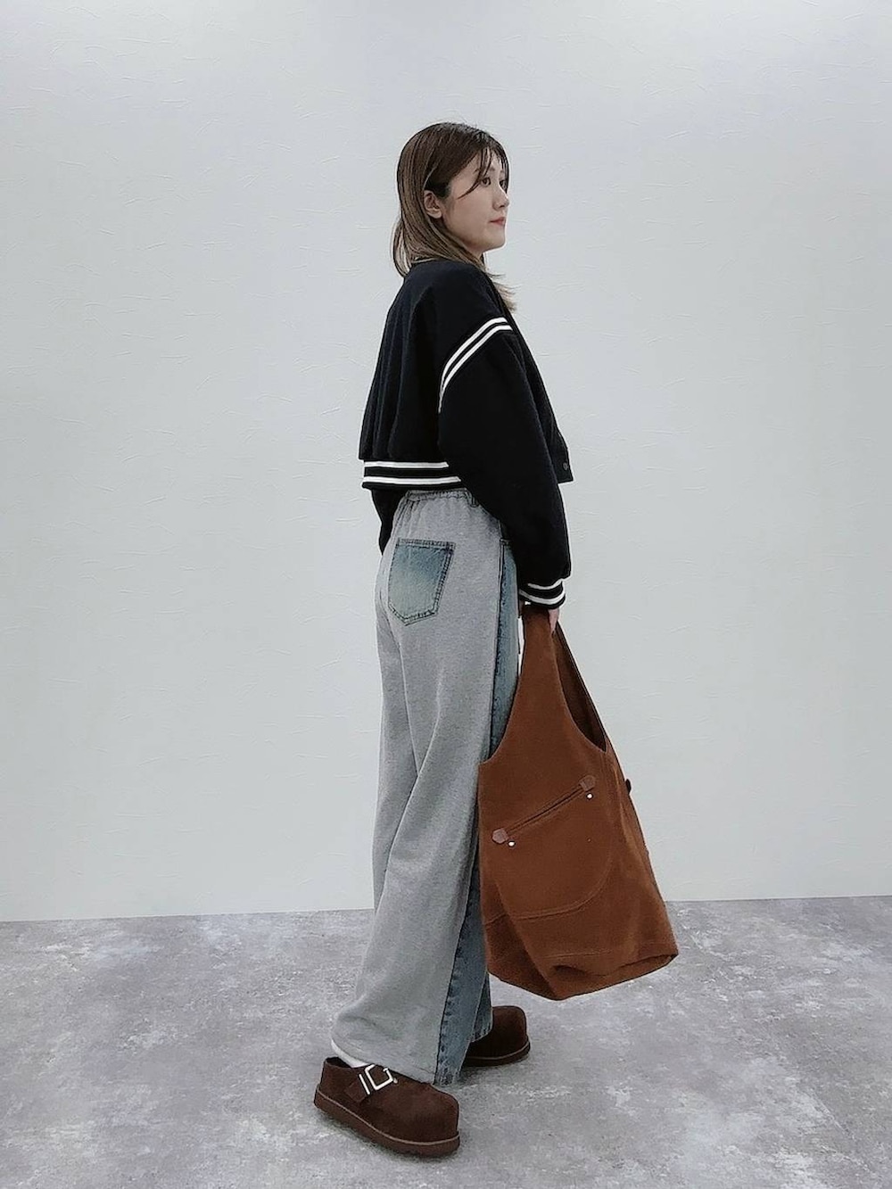 ブラック系のスタジャン、ブルー系のデニムパンツ、ブラウン系のその他シューズを着用したレディースの秋コーディネートの3枚目の写真