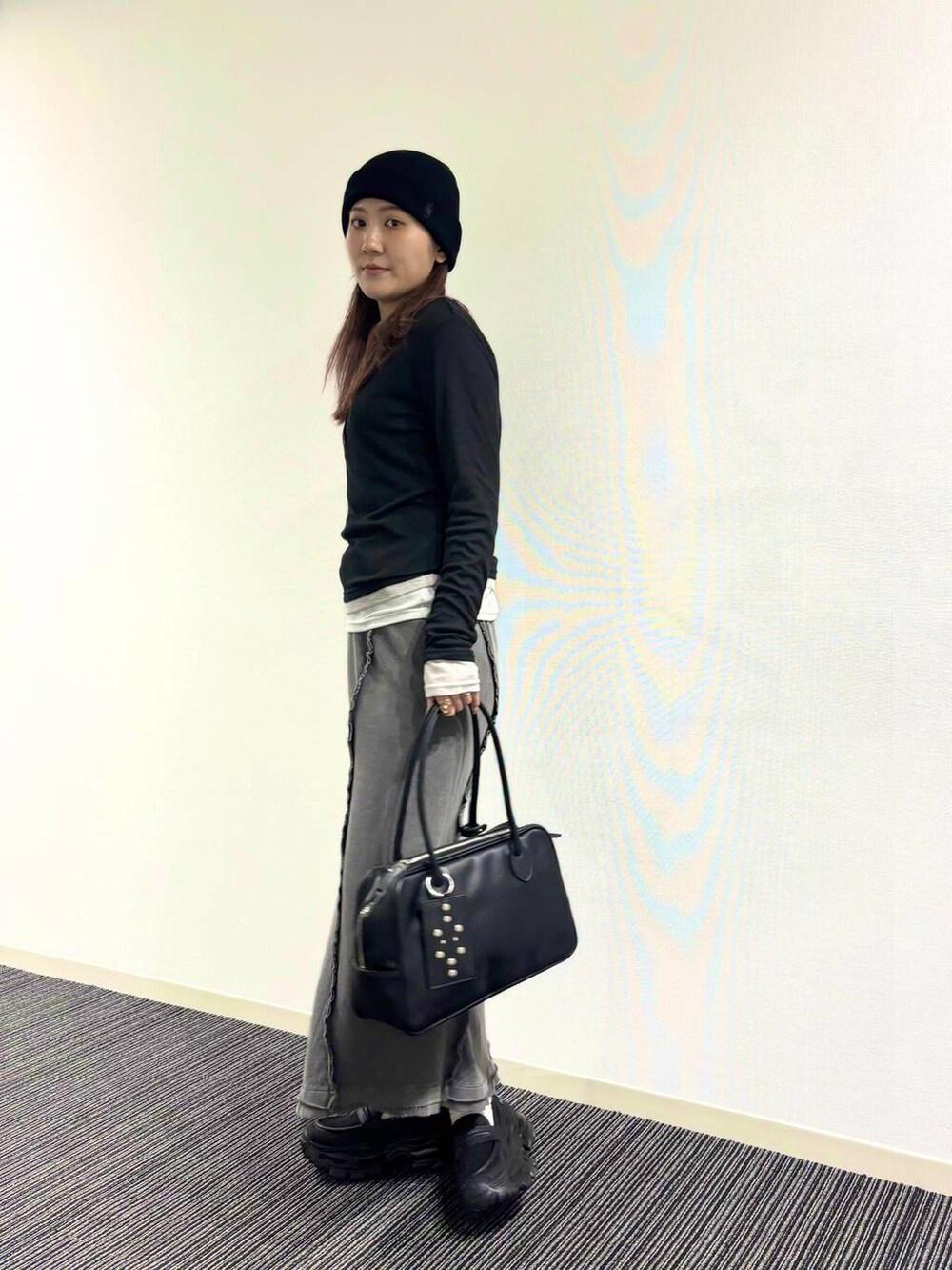 ブラック系のローファー、ブラック系のボストンバッグ、グレー系のスカートを着用したレディースの冬コーディネートの3枚目の写真
