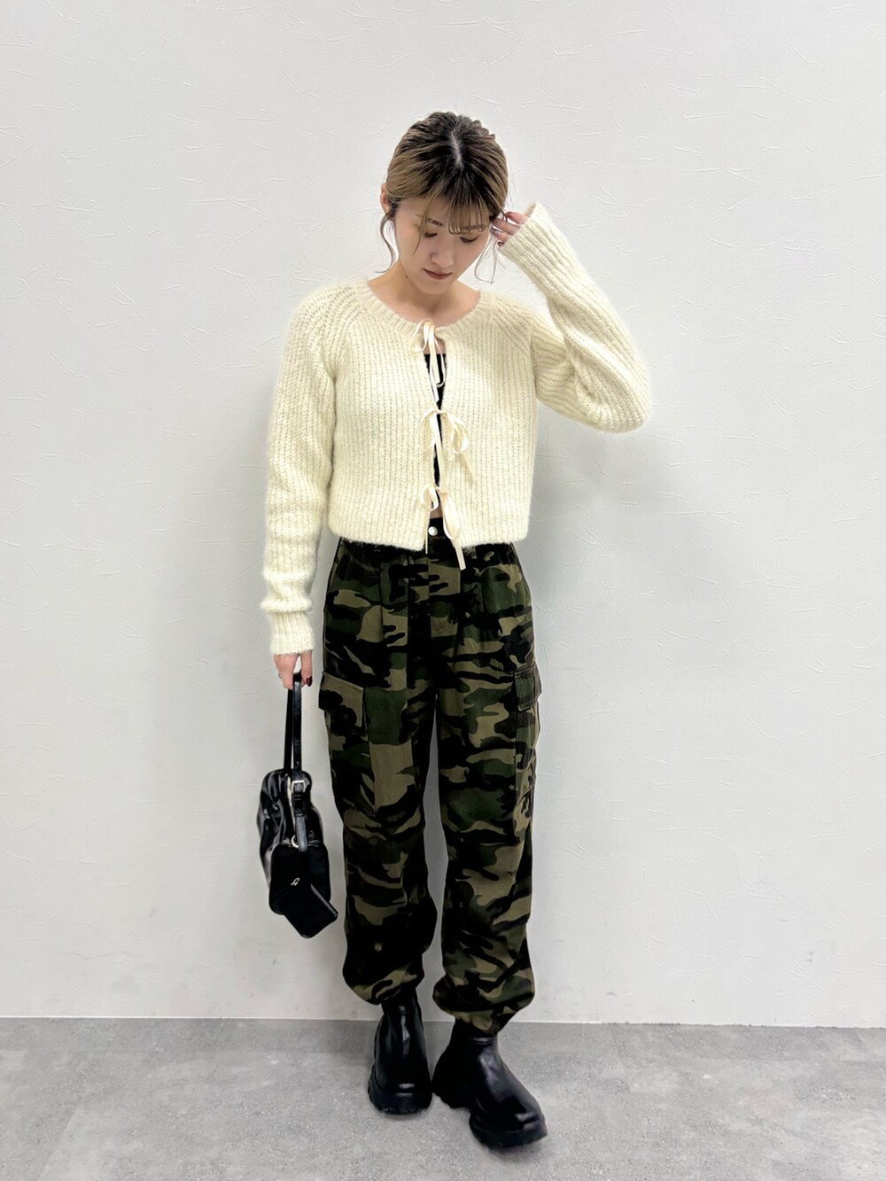 グリーン系のカーゴパンツ、ベージュ系のカーディガン/ボレロ、ブラック系のブーツを着用したレディースの秋コーディネートの3枚目の写真