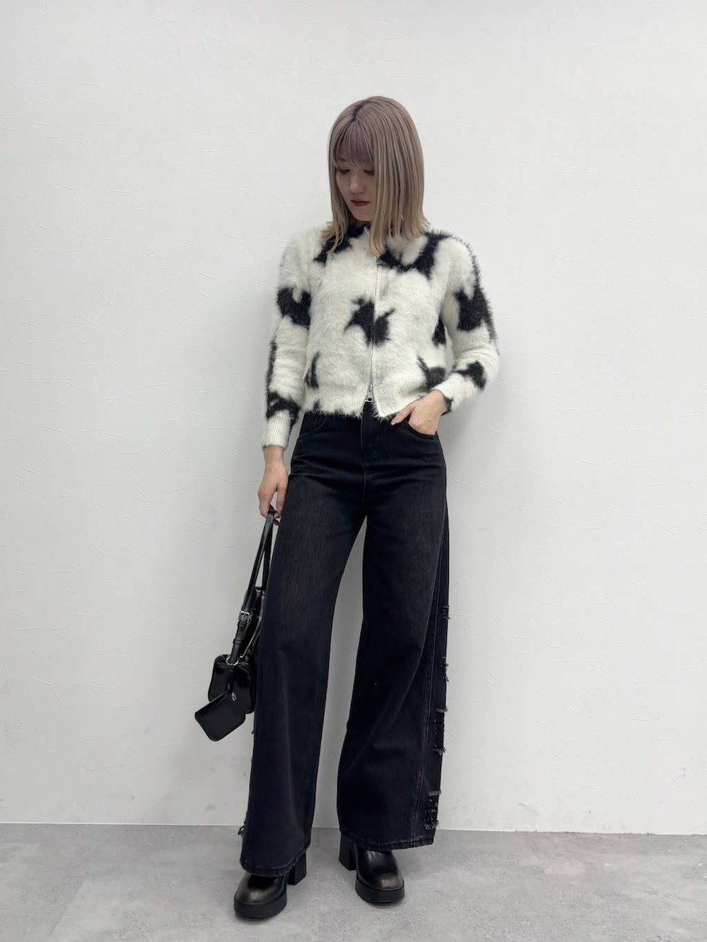 ブラック系のショルダーバッグ、ブラック系のデニムパンツ、ブラック系のブーツを着用したレディースの冬コーディネートの2枚目の写真