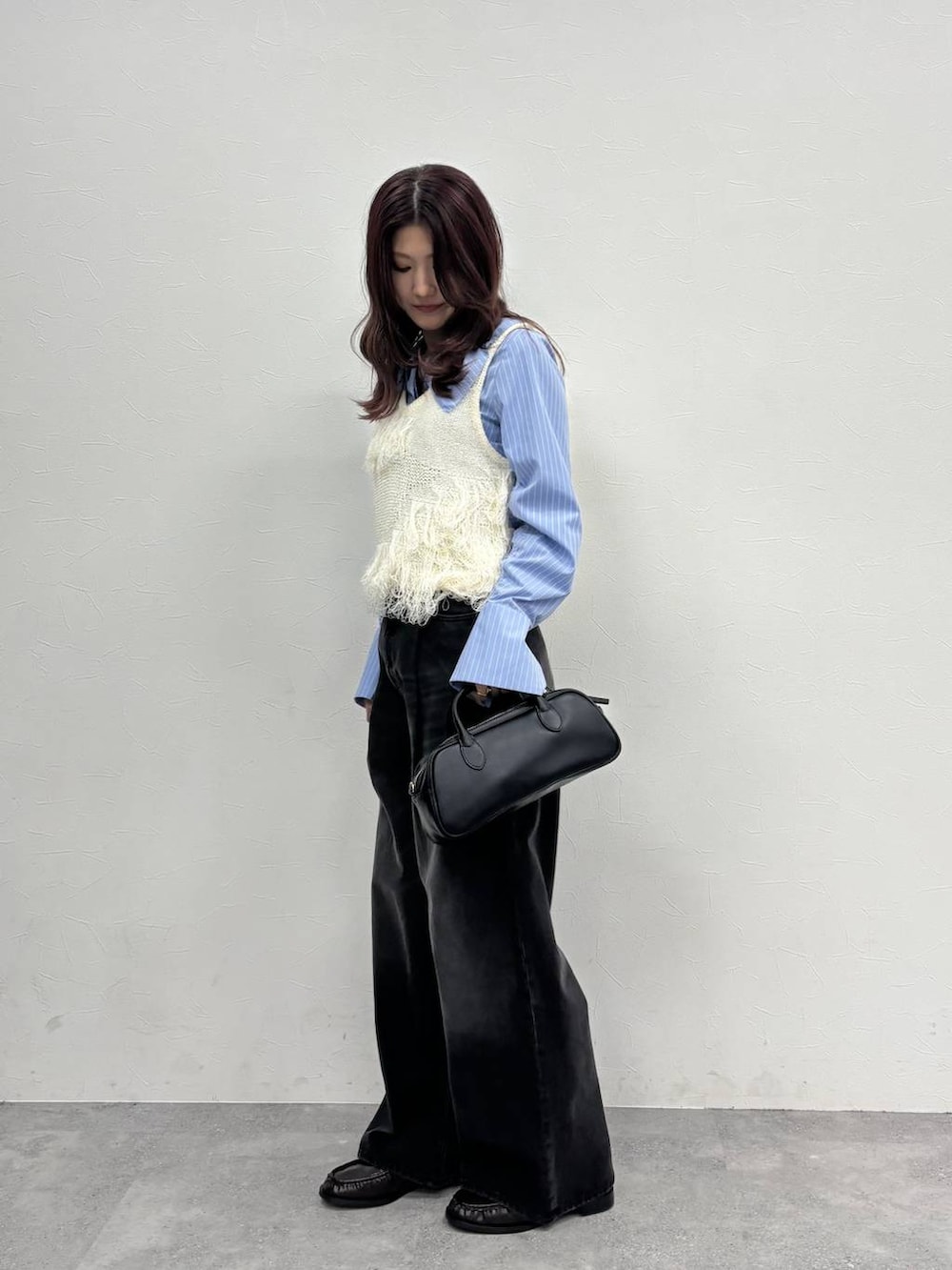 グレー系のデニムパンツ、ブラック系のボストンバッグ、ブラウン系のローファーを着用したレディースの冬コーディネートの3枚目の写真