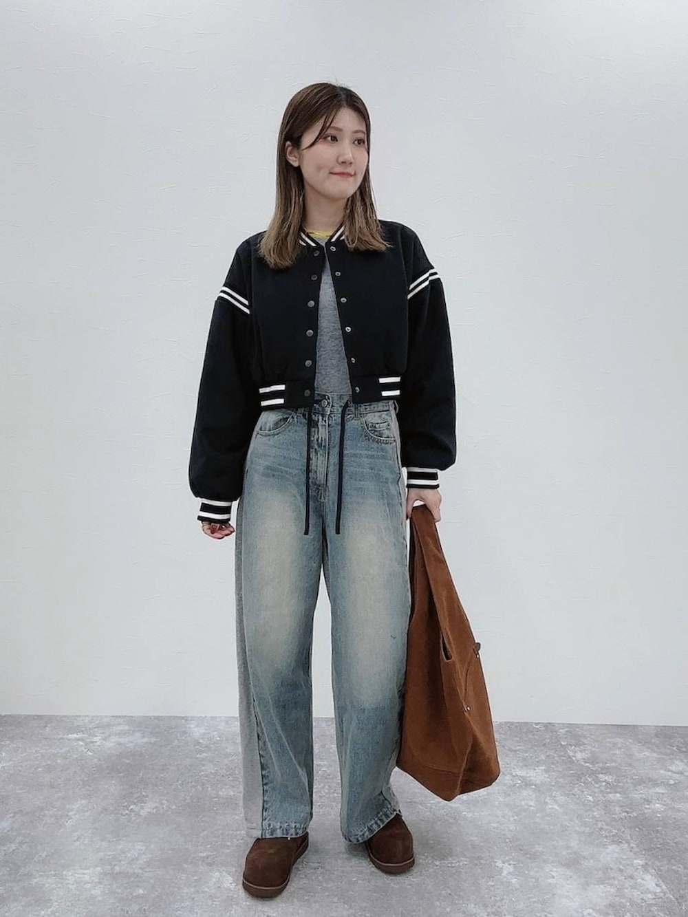 ブラック系のスタジャン、ブルー系のデニムパンツ、ブラウン系のその他シューズを着用したレディースの秋コーディネートの2枚目の写真