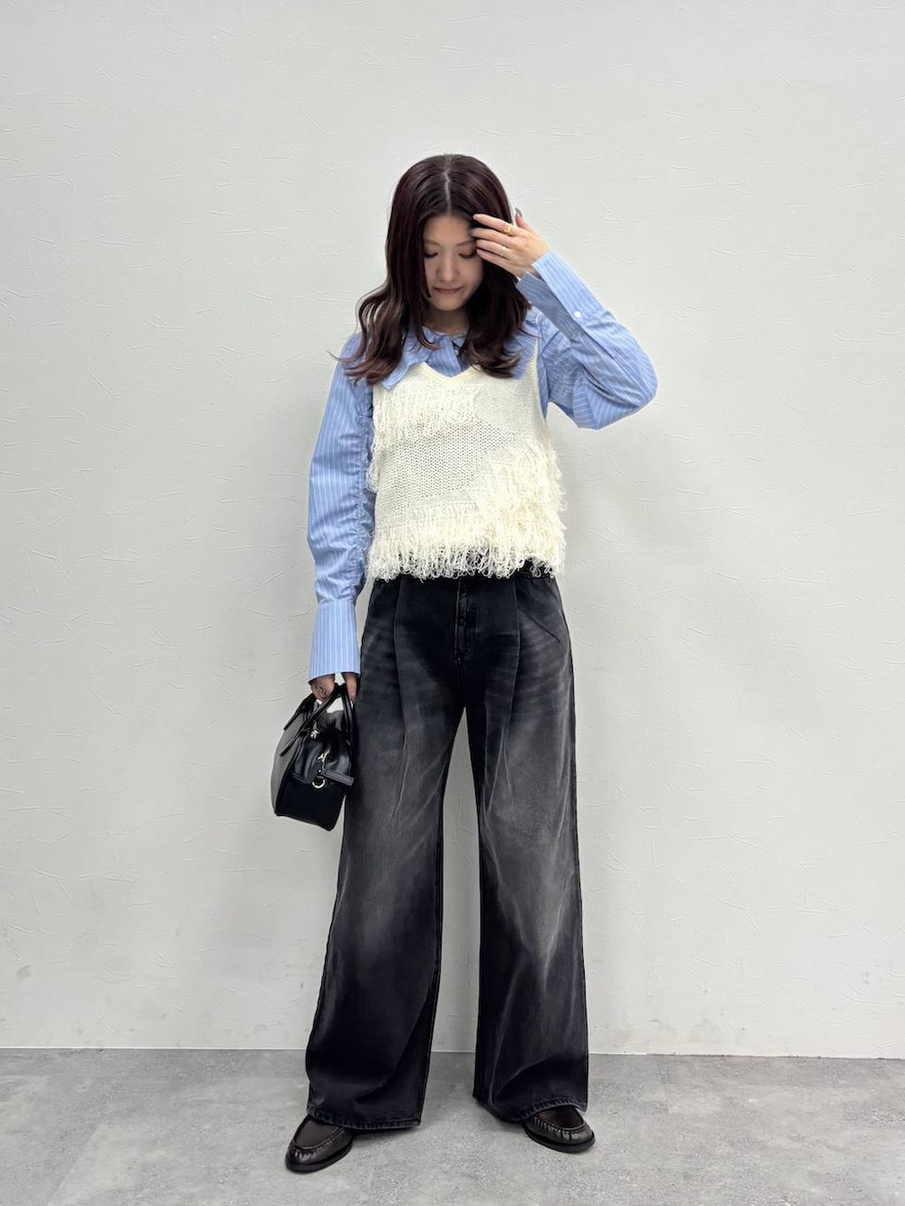 グレー系のデニムパンツ、ブラック系のボストンバッグ、ブラウン系のローファーを着用したレディースの冬コーディネートの2枚目の写真