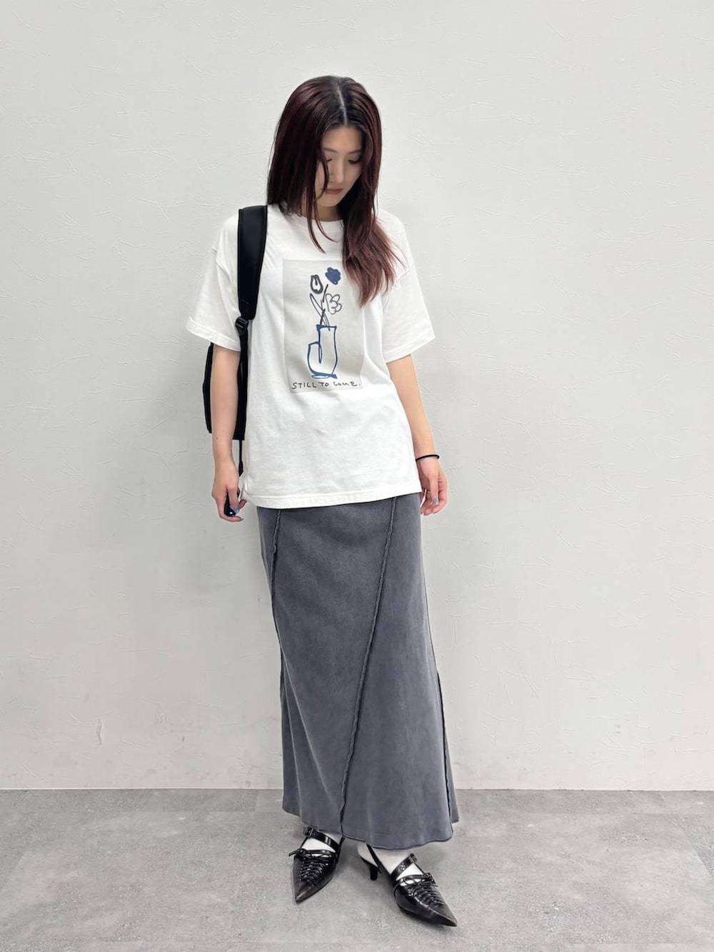 ブラック系のスカート、ホワイト系のTシャツ/カットソー、ブラック系のバックパック/リュックを着用したレディースの夏コーディネートの5枚目の写真