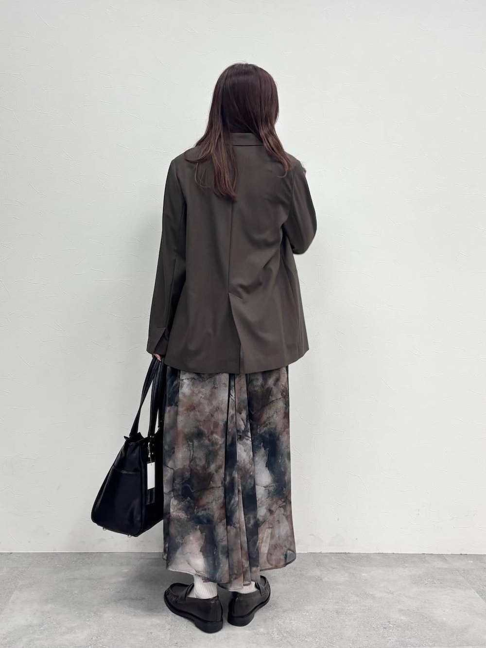 ブラック系のスカート、ブラウン系のテーラードジャケット、ブラック系のトートバッグを着用したレディースの冬コーディネートの4枚目の写真