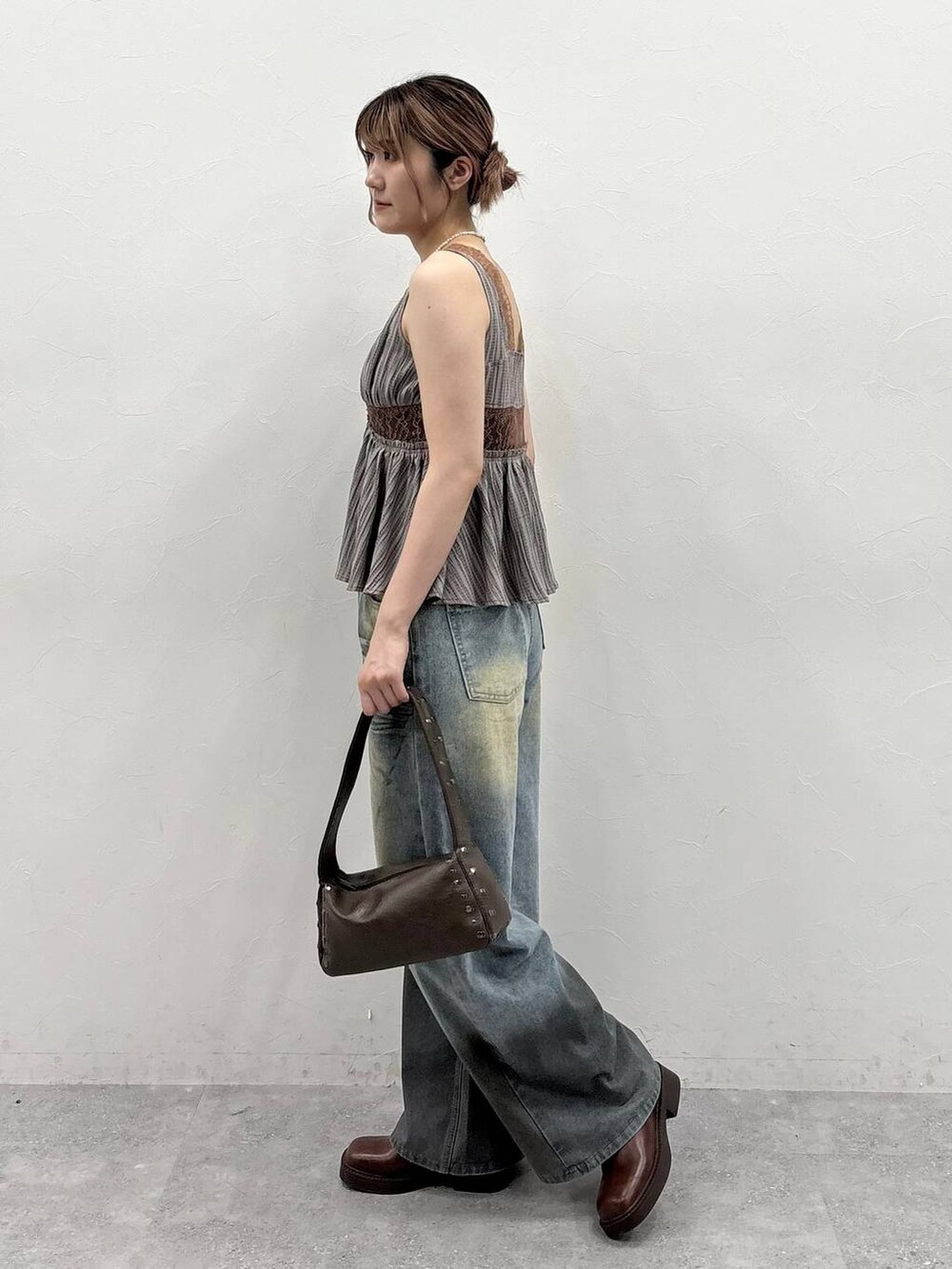 ブラウン系のブーツ、ブルー系のデニムパンツ、ベージュ系のシャツ/ブラウスを着用したレディースの春コーディネートの3枚目の写真