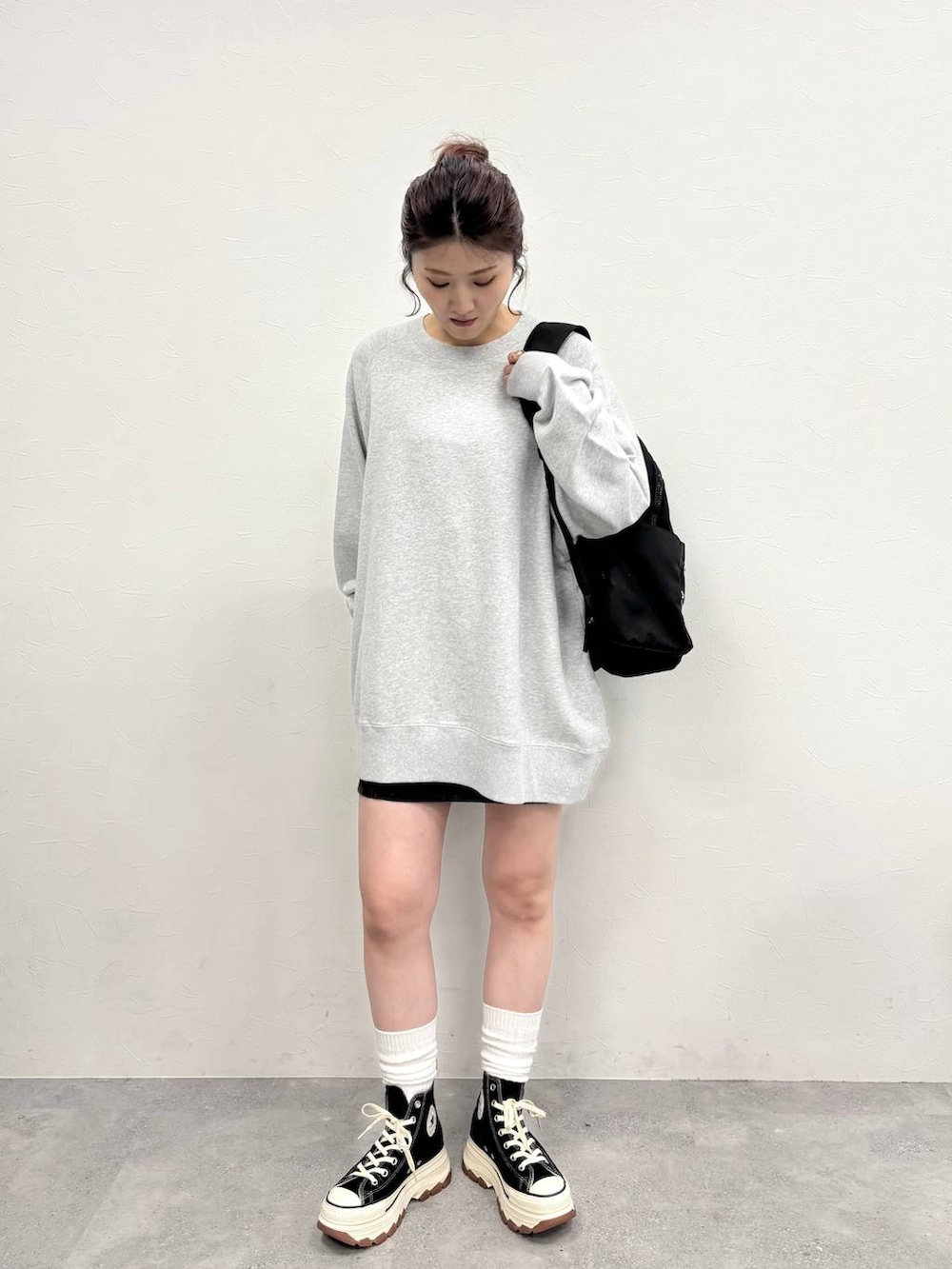 グレー系のスウェット、ブラック系のスニーカー、ブラウン系のデニムスカートを着用したレディースの冬コーディネートの2枚目の写真