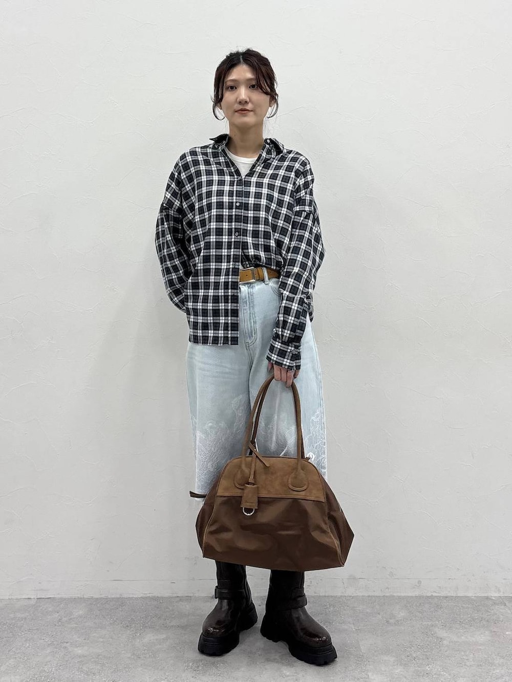 ブラウン系のボストンバッグ、ホワイト系のTシャツ/カットソー、ブラウン系のブーツを着用したレディースの夏コーディネートの2枚目の写真