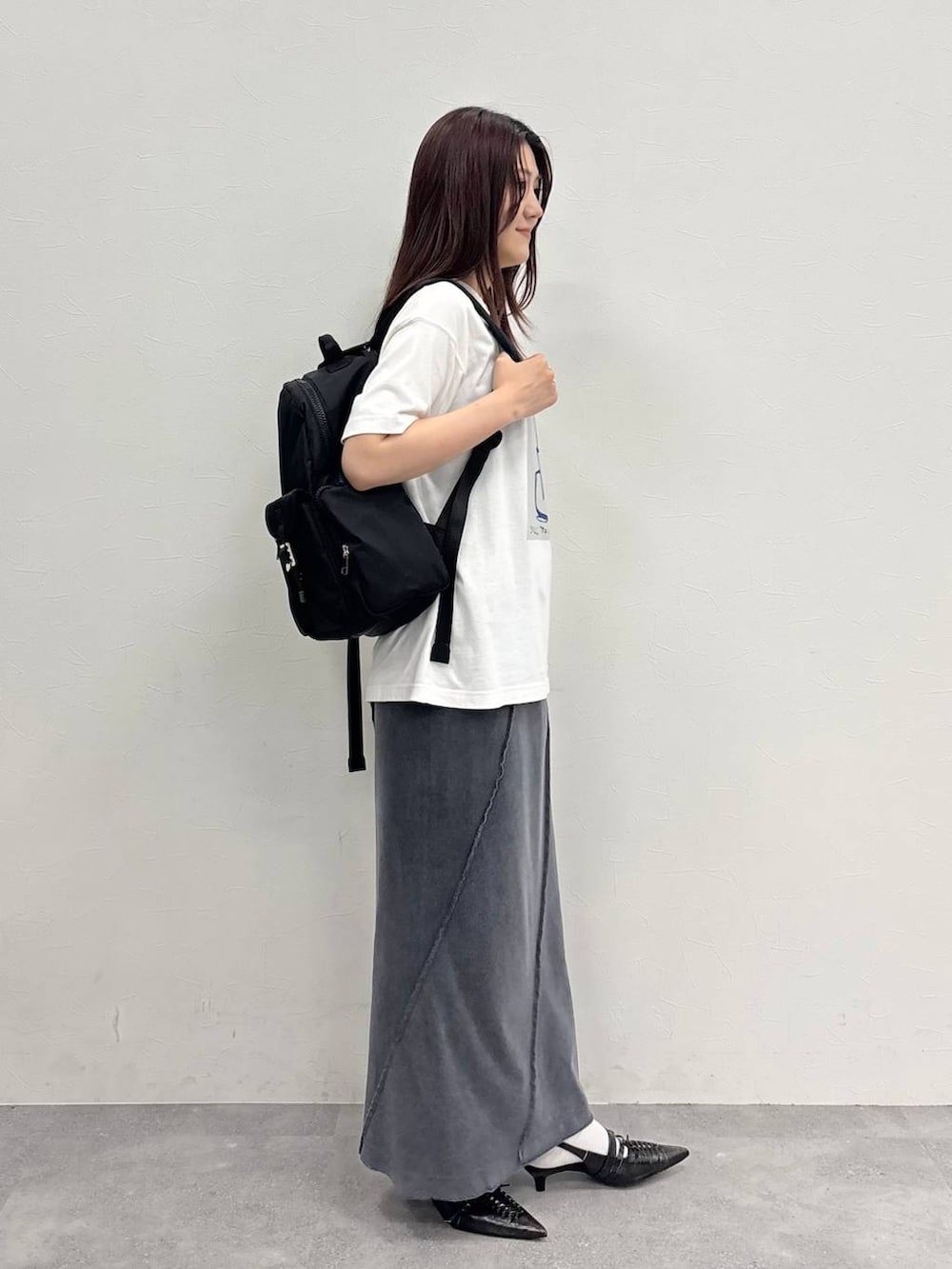 ブラック系のスカート、ホワイト系のTシャツ/カットソー、ブラック系のバックパック/リュックを着用したレディースの夏コーディネートの7枚目の写真